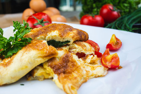 Traditional omelet with vegetables, spinach, tomatoes and herbs on a wooden table in a restaurant....