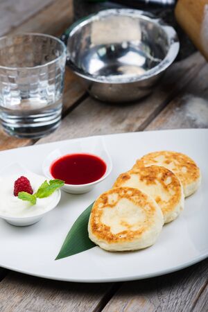 Traditional breakfast with coffee and cheesecakes, cottage cheese pancakes, on a plate with syrup and jam. Creative serving, breakfast in the cafe. Healthy and tasty food.の写真素材