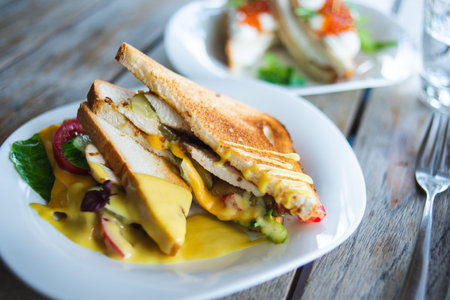 Classic breakfast, hot sandwiches with cheese, vegetables and chicken on a wooden table. Hand-made,...