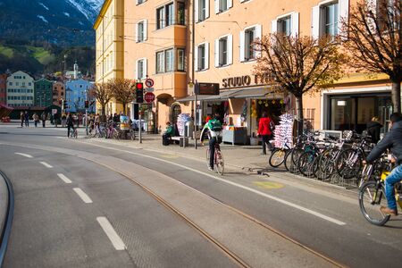 INSBRUK, AUSTRIA - FEBRUARY 2020:Pedestrians, residents and tourists in the narrow streets of the old European city in Austria. Blue sky city landscape. Travel to the Alps.のeditorial素材
