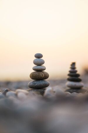 Balanced stone pyramid on pabbles beach with sunset. Zen rock, concept of balance and harmony. Calmness and pacification. Travel and beach vacations. Soft focus and beautiful bokeh. Sky.の写真素材