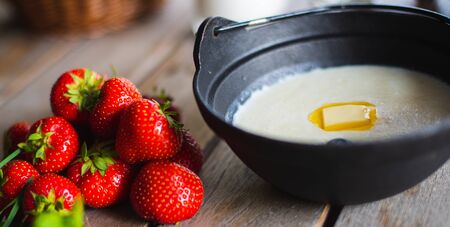 Traditional breakfast. Milk porridge with butter and berries on a wooden table. Classic rustic breakfast, porridge with milk. Healthy tasty food and bright creative serving in the restaurant.の写真素材