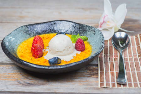 Traditional dessert cream catalana and creme brulee in a beautiful plate on a wooden table in a restaurant or cafe.の写真素材