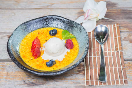 Traditional dessert cream catalana and creme brulee in a beautiful plate on a wooden table in a restaurant or cafe.の写真素材