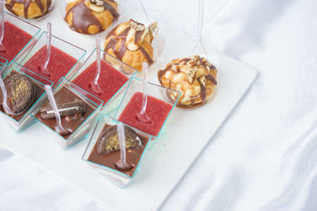 Sweet little desserts cakes in different colors on a plate prepared for the guests of the event.の写真素材