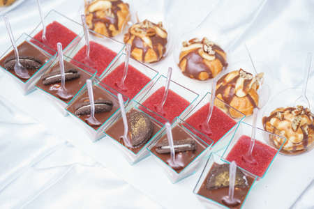 Sweet little desserts cakes in different colors on a plate prepared for the guests of the event.の写真素材
