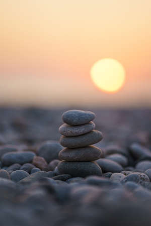 Balanced stone pyramid on pabbles beach with sunset. Zen rock, concept of balance and harmony.の写真素材