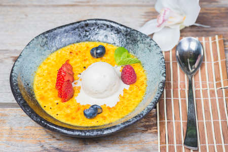 Traditional dessert cream catalana and creme brulee in a beautiful plate on a wooden table in a restaurant or cafe.の写真素材