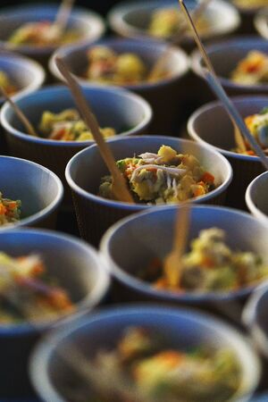 Original serving of light snacks in paper cups. Catering and guest meals during the event. Quick mini snacks in a special beautiful dish. Canapes and light meals, tapas on the table.の写真素材