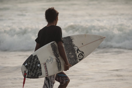 BALI, INDONESIA-MARCH 2020: Young people ride with short board look on the waves during sunset....