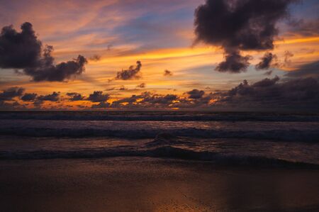 Magical dramatic sunset on a tropical beach. Seascape, ocean waves and bright clouds in the sky. Golden hour. Rest on the seashore, beach vacation. Concept.の写真素材