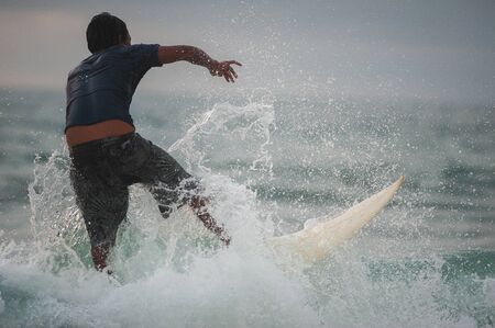 Young people ride on short boards, perform tricks on the waves. Extreme sports and hobbies. Ocean waves. Soft focus and blurry photos while moving.の写真素材