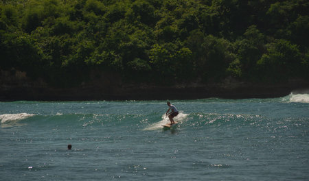 Young people ride on short boards, perform bright tricks on the waves during sunset.