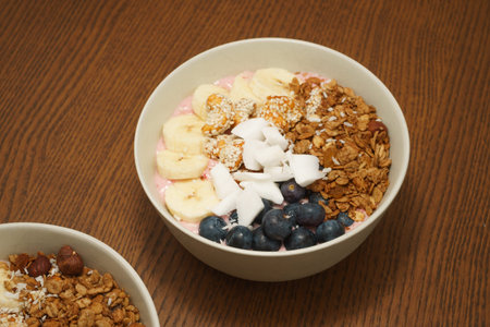 Handmade Bowl with healthy tasty breakfast of yogurt, smoothie with granola, nuts, bananas and...