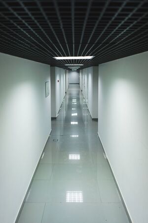 Interior internal corridor of modern office, industrial premises, laboratories or institutions. Corridor with light walls, black ceiling and shiny floor. Soft focus.の写真素材