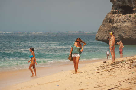BALANGAN Beach, BALI, INDONESIA-SPRING, 2020: Vacationing young people are sunbathing sandy beach. Travel and beach holidays on a tropical island. Families children and people on beach by cliff.のeditorial素材