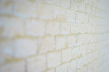 White brick wall abstract background. Brickwork close up. A brick wall illuminated by a different light. Soft focus and bokeh.の写真素材