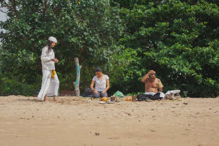BALI, INDONESIA-APRIL, 2020: Traditional Balinese blessing ceremony by ocean, featuring newlyweds and an elder, shaman, monk or clergyman. Priest conduct the ceremony on the shore. Soft focus.のeditorial素材