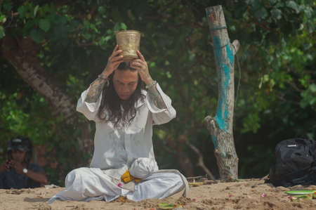 BALI, INDONESIA-APRIL, 2020: Traditional Balinese blessing ceremony by ocean, featuring newlyweds and an elder, shaman, monk or clergyman. Priest conduct the ceremony on the shore. Soft focus.のeditorial素材