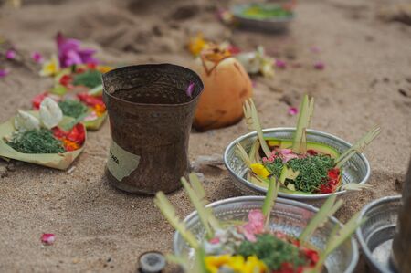 Traditional symbols and offerings to the gods during Balinese blessing ceremony on ocean with newlyweds and clergyman. Priest conduct ceremony on the shore. Soft focus.の写真素材