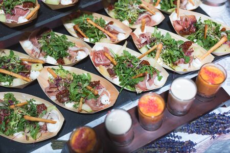Small plates with appetizer, salad for guests of the event and celebration. Catering guest meals during event. Quick mini snacks dish. Chopped sticks of vegetables sauce.の写真素材