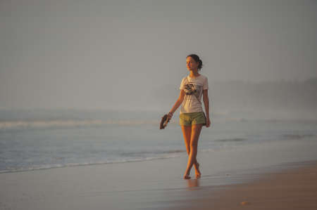 KUTA, INDONESIA - SPRING, 2020: Tourists and residents of Kuta, Semenyak, Jimbaran on a sandy beach during sunset. Active, beach holidays in Asian countries. Landscape Bali Thailand. Soft focus. Lots of tourists on the beach.のeditorial素材