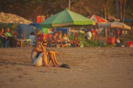 KUTA, INDONESIA - SPRING, 2020: Tourists and residents of Kuta, Semenyak, Jimbaran on a sandy beach during sunset. Active, beach holidays in Asian countries. Landscape Bali Thailand. Soft focus. Lots of tourists on the beach.のeditorial素材