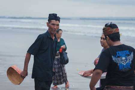 BALI, INDONESIA-APRIL, 2020: Traditional Balinese blessing ceremony by ocean elder, shaman, monk or clergyman. Priest conduct the ceremony on shore. Soft focus.のeditorial素材