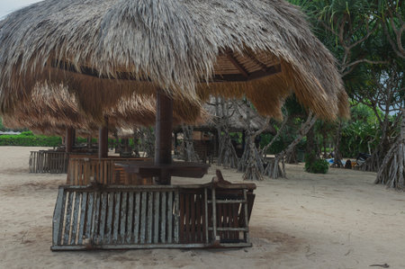 Beach umbrellas from straw on tropical sandy beach. Sea waves and empty sandy beach at sunset. Vacation, travel concept.の写真素材