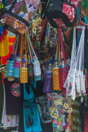 KUTA, BALI, INDONESIA-APRIL, 2020: Indonesians locals and street market employees sell souvenirs, cheap clothes, and food. Environment and society. Poverty and cheap goods. Travel to Asia.のeditorial素材