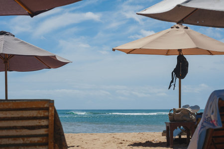 Tropical landscape: sunbeds and parasols on the beach. Seascape view of empty beach and ocean early...