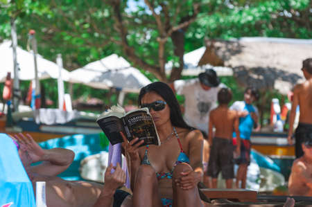 NUSA DUA, BALI, INDONESIA-SPRING, 2020: Vacationing young people are sunbathing Nusa Dua sandy beach. Travel and beach holidays on a tropical island. Families children and people.のeditorial素材