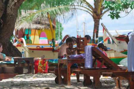NUSA DUA, BALI, INDONESIA-SPRING, 2020: Vacationing young people are sunbathing Nusa Dua sandy beach. Travel and beach holidays on a tropical island. Families children and people.のeditorial素材