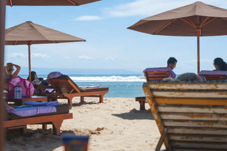 NUSA DUA, BALI, INDONESIA-SPRING, 2020: Vacationing young people are sunbathing Nusa Dua sandy beach. Travel and beach holidays on a tropical island. Families children and people.のeditorial素材