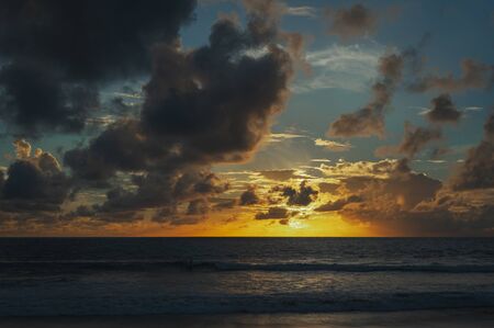 Magical dramatic sunset on a tropical beach. Seascape, ocean waves and bright clouds in the sky. Golden hour. Rest seashore, beach vacation. Concept. Clouds in the sky are painted in different colors.の写真素材