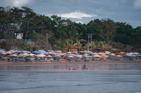 KUTA, BALI - APRIL, 2020: Children play on the beach by the ocean, build a sand castle. Entertainment for children. Travel to Asia. Beach on the island of bali. Soft focus, tinted.のeditorial素材