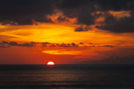 Tropical seascape. Stunning dramatic sunset over the ocean. Huge cumulus clouds colored by the setting sun. Beach holidays with sea views in the evening.の写真素材