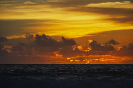 Magical dramatic sunset on a tropical beach. Seascape, ocean waves and bright clouds in the sky. Golden hour. Rest on the seashore, beach vacation. Concept.の写真素材