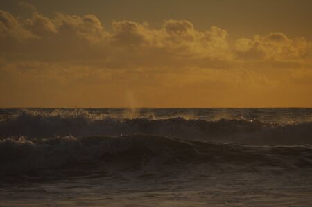 Magical dramatic sunset on a tropical beach. Seascape, ocean waves and bright clouds in the sky. Golden hour. Rest on the seashore, beach vacation. Concept.の写真素材