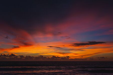 Magical dramatic sunset on a tropical beach. Seascape, ocean waves and bright clouds in the sky. Golden hour. Rest seashore, beach vacation. Concept. Clouds in the sky are painted in different colors.の写真素材