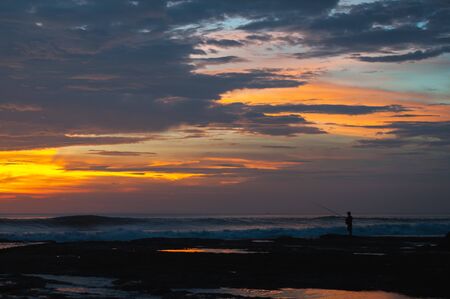 Tropical seascape. Stunning dramatic sunset over the ocean. Huge cumulus clouds colored by the setting sun. Walk along the beach.の写真素材