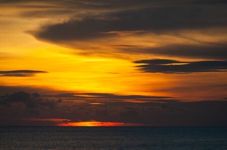 Tropical seascape. Stunning dramatic sunset over the ocean. Huge cumulus clouds colored by the setting sun. Beach holidays with sea views in the evening.の写真素材