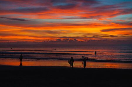 Magical dramatic sunset on tropical beach. Black silhouette of a surfer with a board on background ocean and sky during sunset. Seascape, ocean wave. Soft focus, no noise reduction.の写真素材