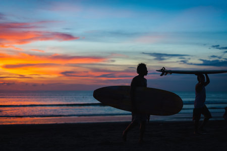 Magical dramatic sunset on tropical beach. Black silhouette of a surfer with a board on background ocean and sky during sunset. Seascape, ocean wave. Soft focus, no noise reduction.の写真素材
