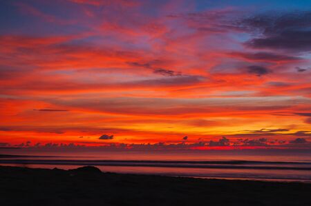 Tropical seascape. Stunning dramatic sunset over the ocean. Huge cumulus clouds colored by the setting sun. Beach holidays with sea views in the evening.の写真素材