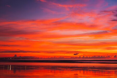 Tropical seascape. Stunning dramatic sunset over the ocean. Huge cumulus clouds colored by the setting sun. Beach holidays with sea views in the evening.