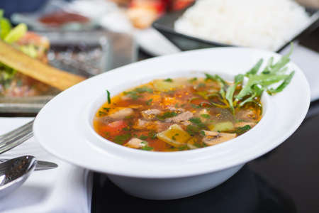 Traditional vegetable soup broth in a white plate on a table in a restaurant.の写真素材
