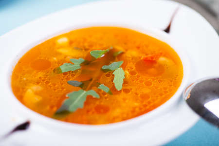Traditional vegetable soup broth in a white plate on a table in a restaurant.の写真素材