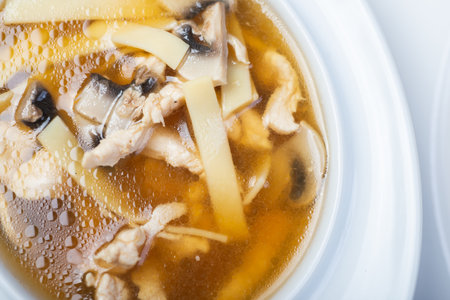 Traditional soup with meat broth in a white plate on a table in a restaurant. Complete and varied food. Soft focus and beautiful bokeh. Complex lunch.の写真素材