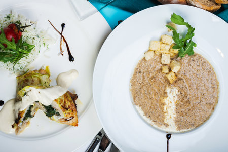 Multi-course set lunch. Mushroom soup, white fish fillet with herbs and rice, salad with chicken breast and vegetables. Complete and healthy food. Lunch is served on table in restaurant. Soft focus.の写真素材